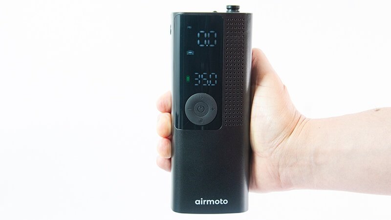 A branded Airmoto portable tire inflator held in one hand